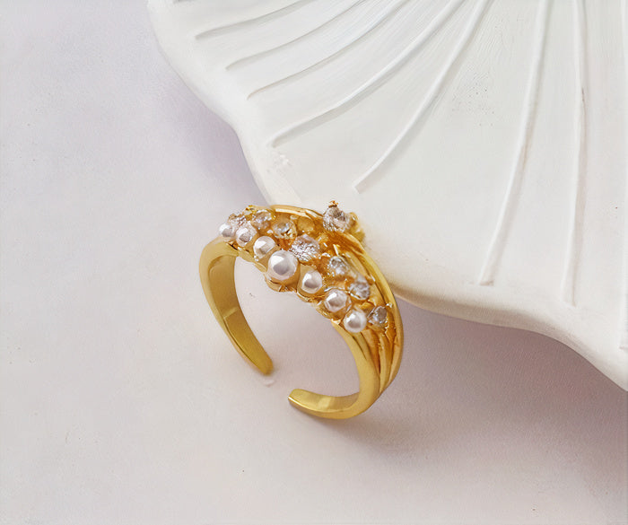 Open goudkleurige ring met parellook en groene kristalaccenten