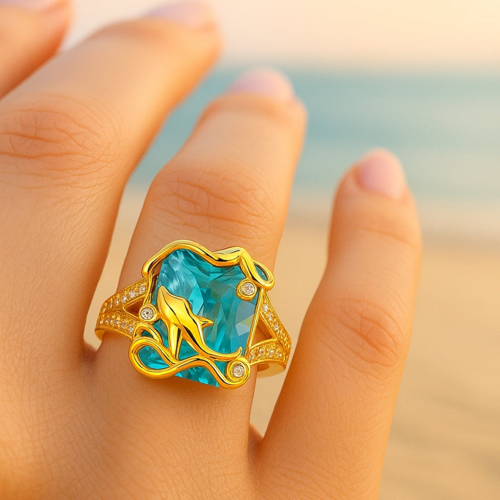 Goudkleurige dolfijnring met blauw kristal
