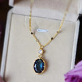 Ketting met blauwe ovale steenhanger en kristallen ophangoog