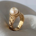 Solitairring met parellook en gegraveerde goudkleurige band