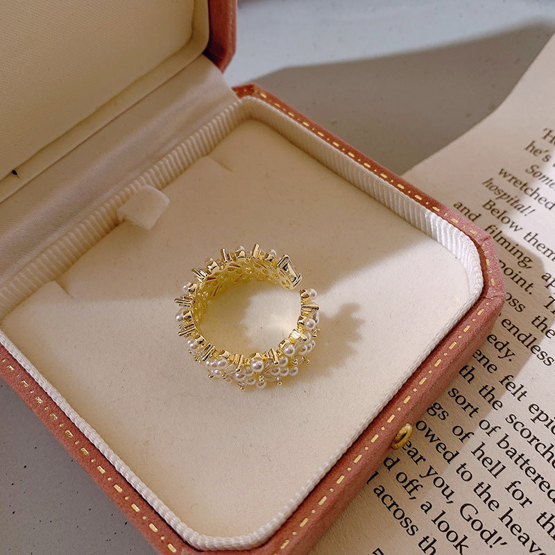 Goudkleurige clusterring met rijen parellook en kristal