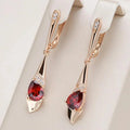 Goudkleurige set van hanger en oorbellen met rood kristal