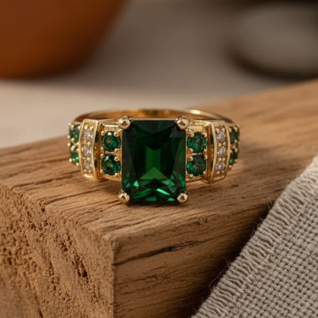 Brede goudkleurige ring met groot groen kristal en railzetting-accenten