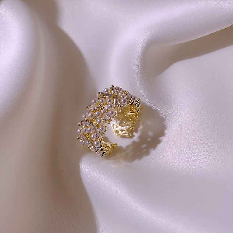 Goudkleurige clusterring met rijen parellook en kristal