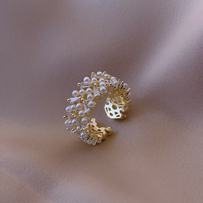 Goudkleurige clusterring met rijen parellook en kristal