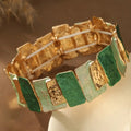 Goudkleurige armband met een spoor van groene stenen