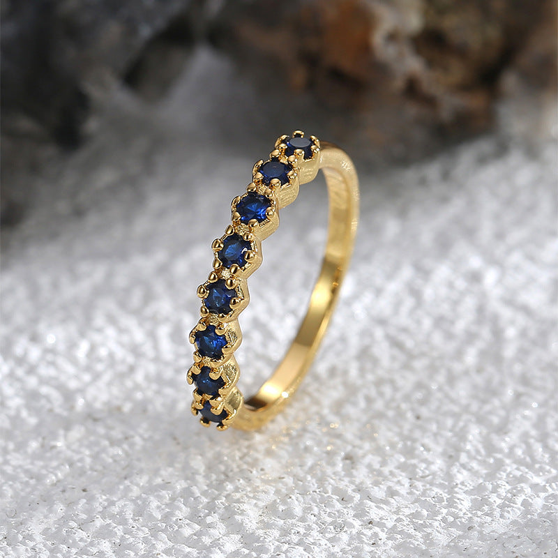 Goudkleurige ring in half-eternitystijl met donkerblauwe stenen