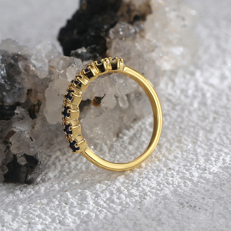 Goudkleurige ring in half-eternitystijl met donkerblauwe stenen