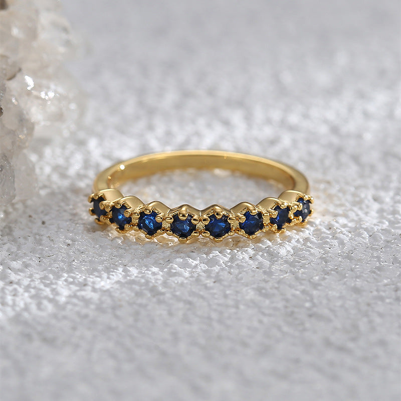 Goudkleurige ring in half-eternitystijl met donkerblauwe stenen