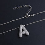 Ketting met bubbelletter-initiaal in twee metaalkleuren