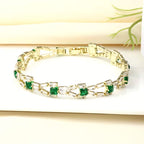 Tennisarmband met schakels en groene stenen in goudkleur