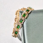 Smaragdgroene stenen schakelarmband in goudkleur