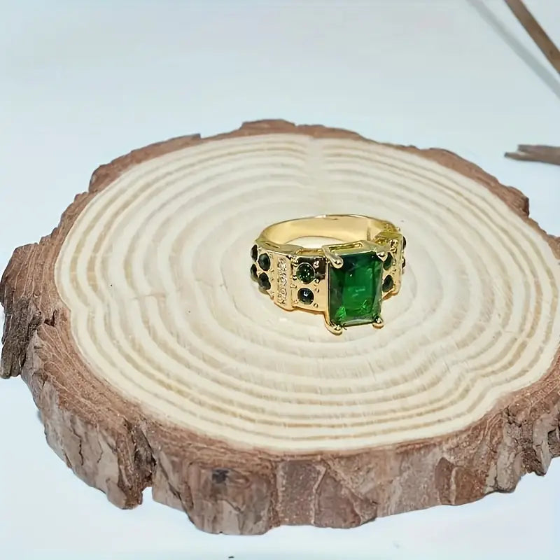 Ring met smaragdgeslepen groen kristal en goudkleurige schouders met kristallen