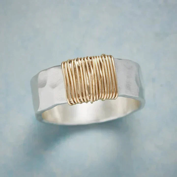 Zilverkleurige bandring met gewikkeld goudkleurig draad in het midden
