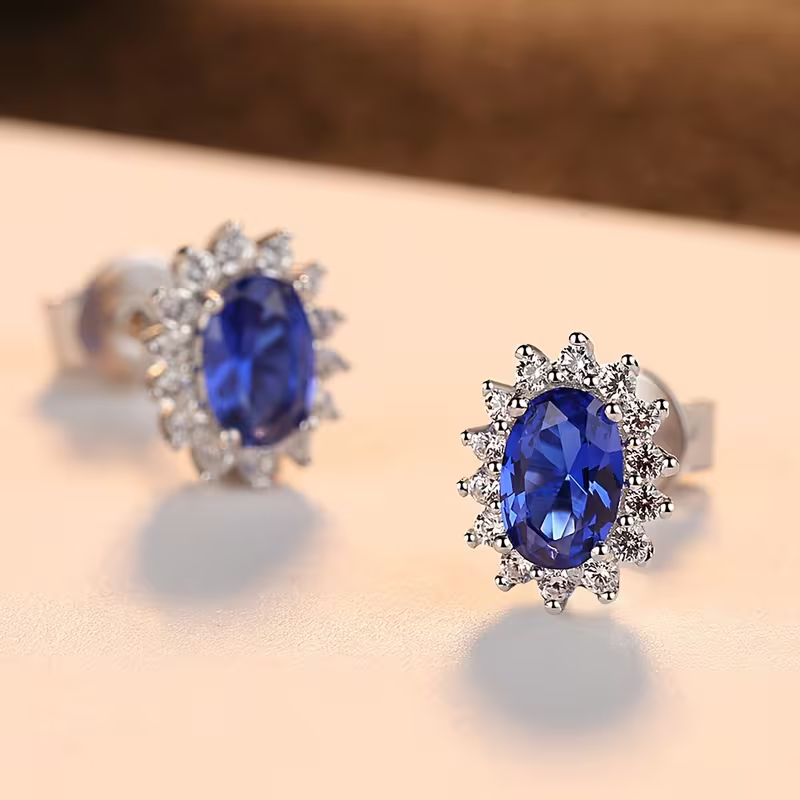 Oorknopjes met blauwe ovale steen en zonnestraal-halo