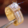 Brede goudkleurige ring met vierkant kristal en baguetterijen