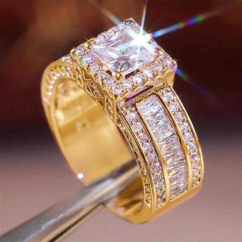 Brede goudkleurige ring met vierkant kristal en baguetterijen