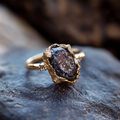 Gesmede goudkleurige ring met donker glas