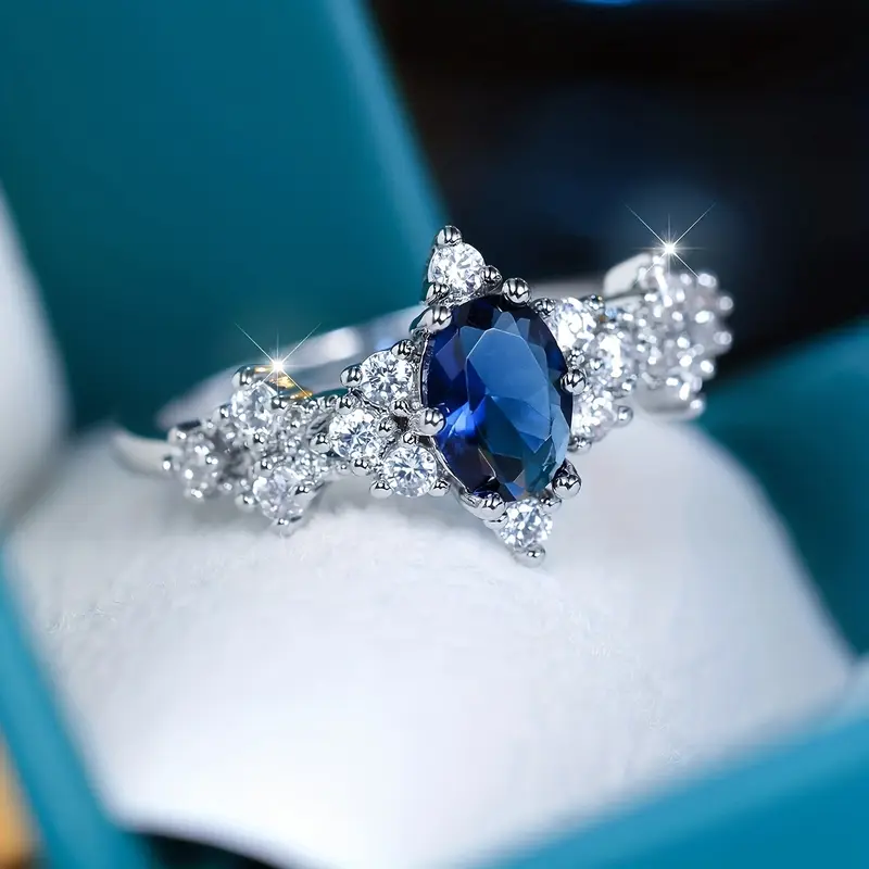 Stralende zilverkleurige ring met ovaal blauw kristal