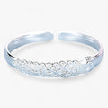 Open pauwarmband met uitwaaierend detail